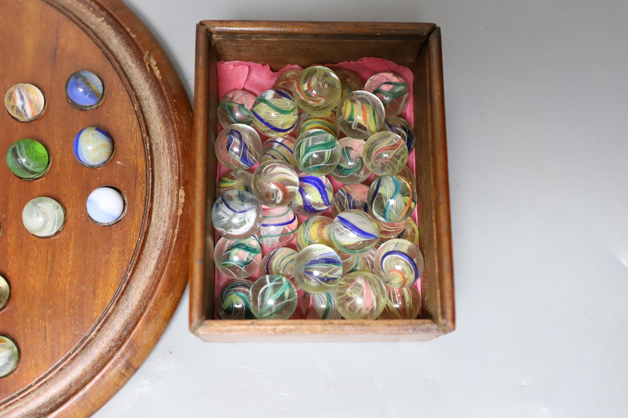 A mahogany solitaire board and marbles